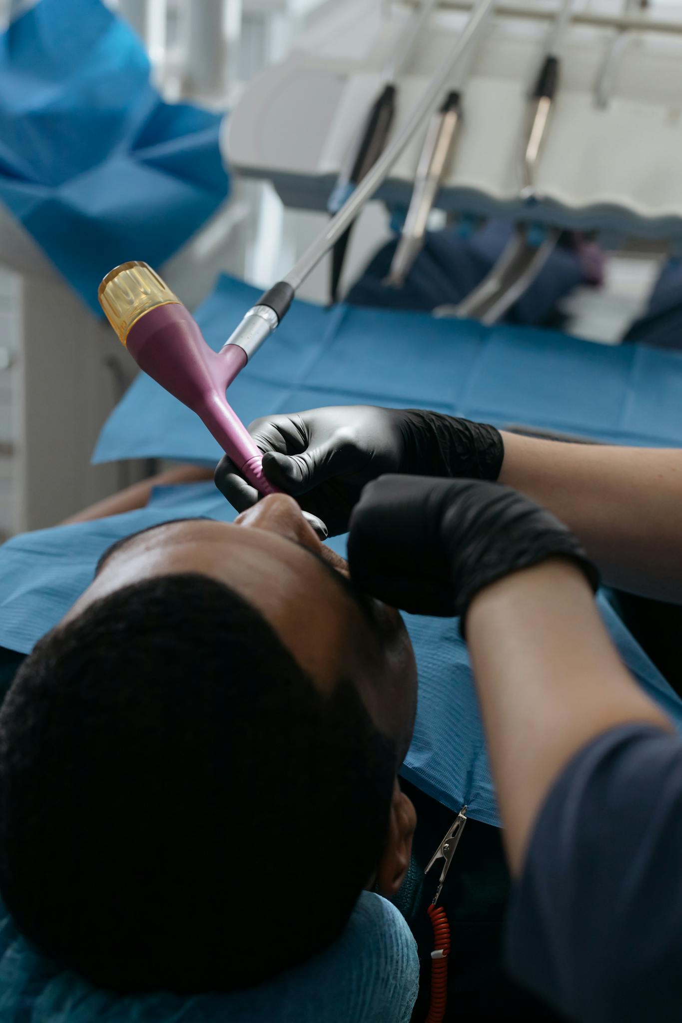 A dentist performing a dental checkup with specialized tools in a clinic setting.