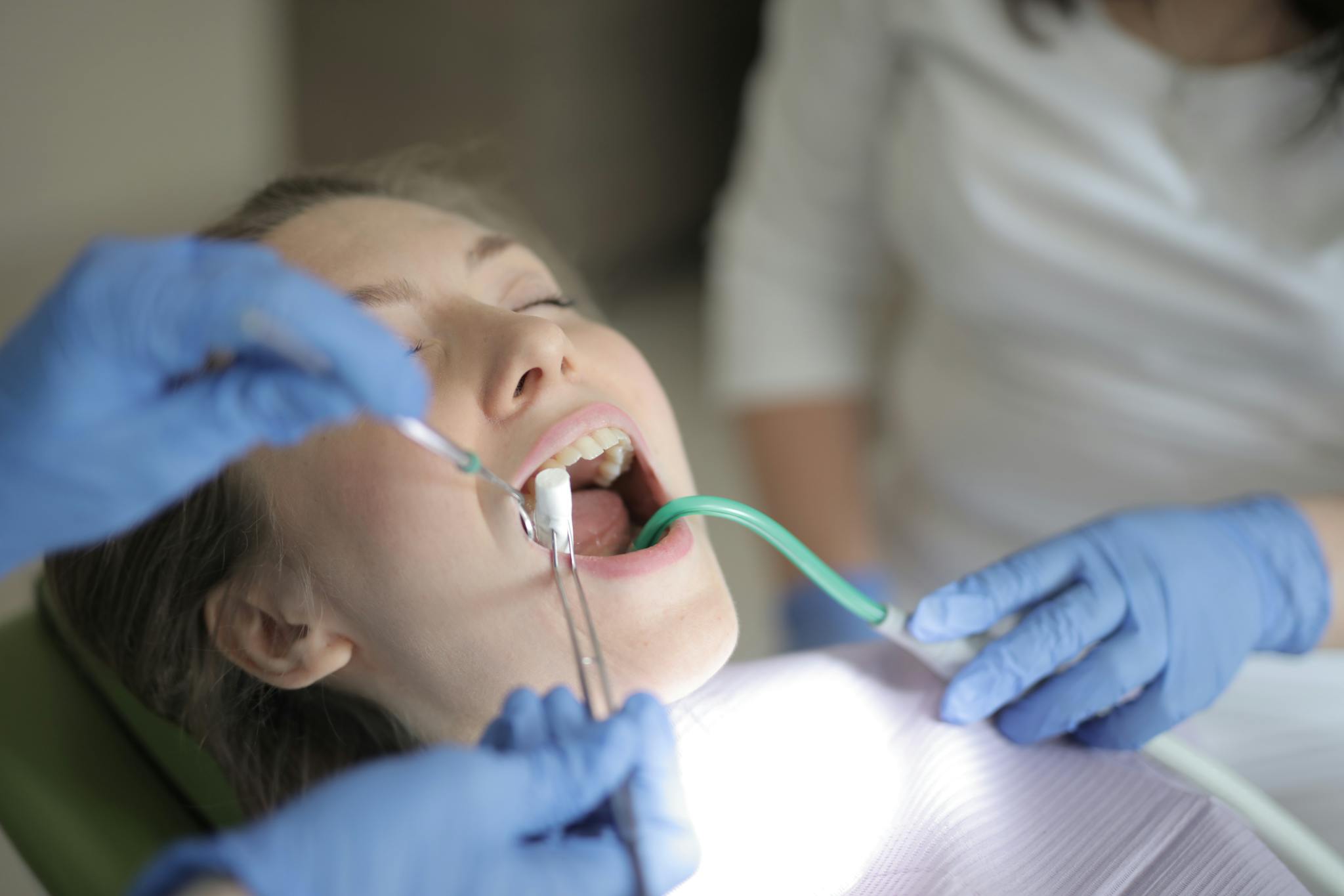 Dentist examines a patient using tools in a clinical setting.